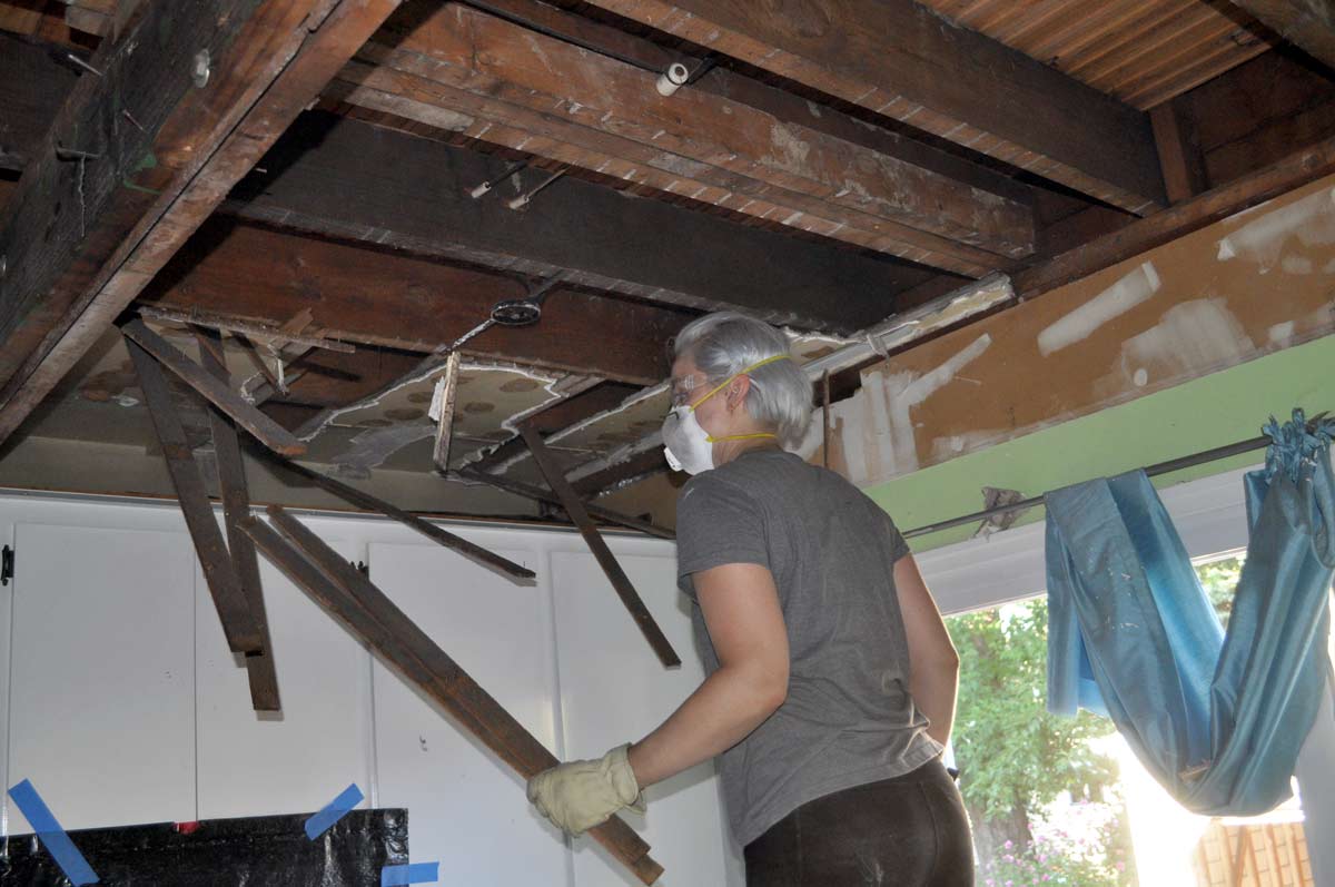 Using a crowbar to remove drywall, plaster, and lath under a drop ceiling